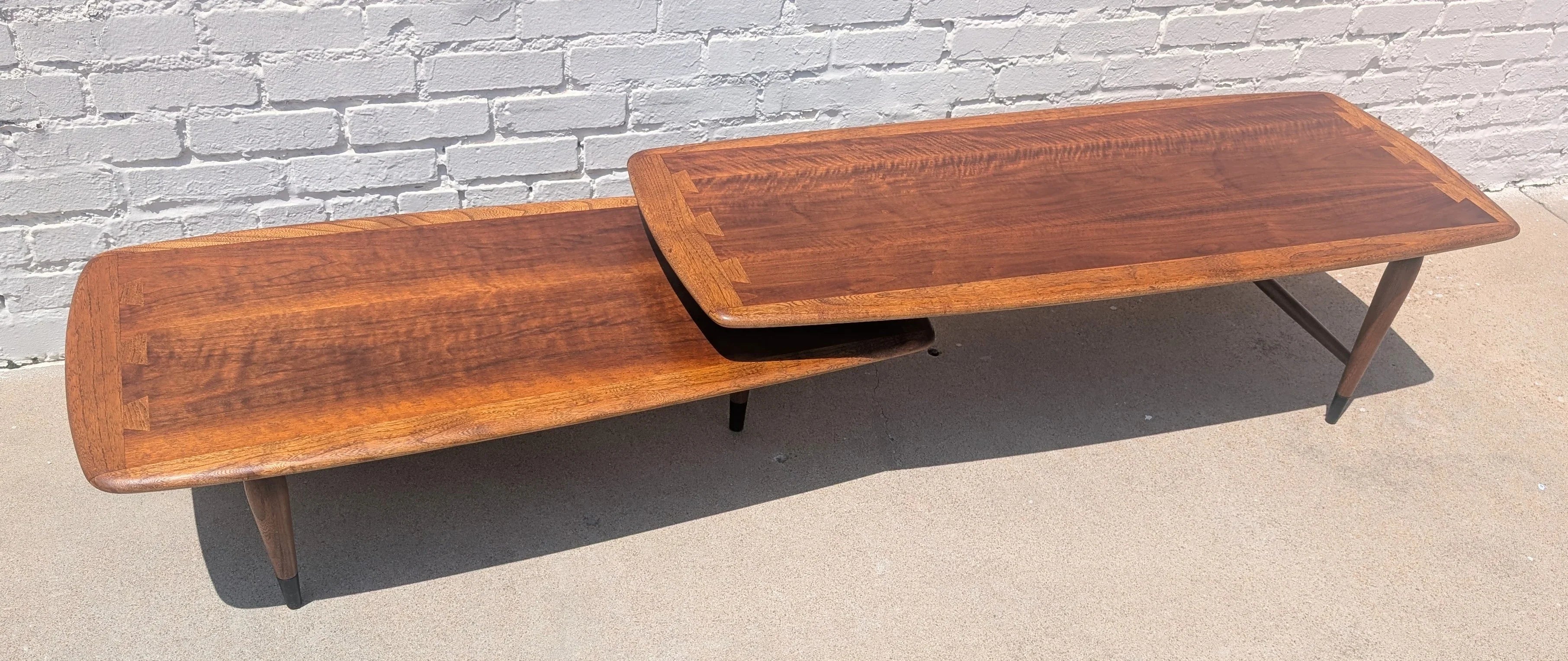 Wooden coffee table with a reflective surface on a concrete floor against a white brick wall.
