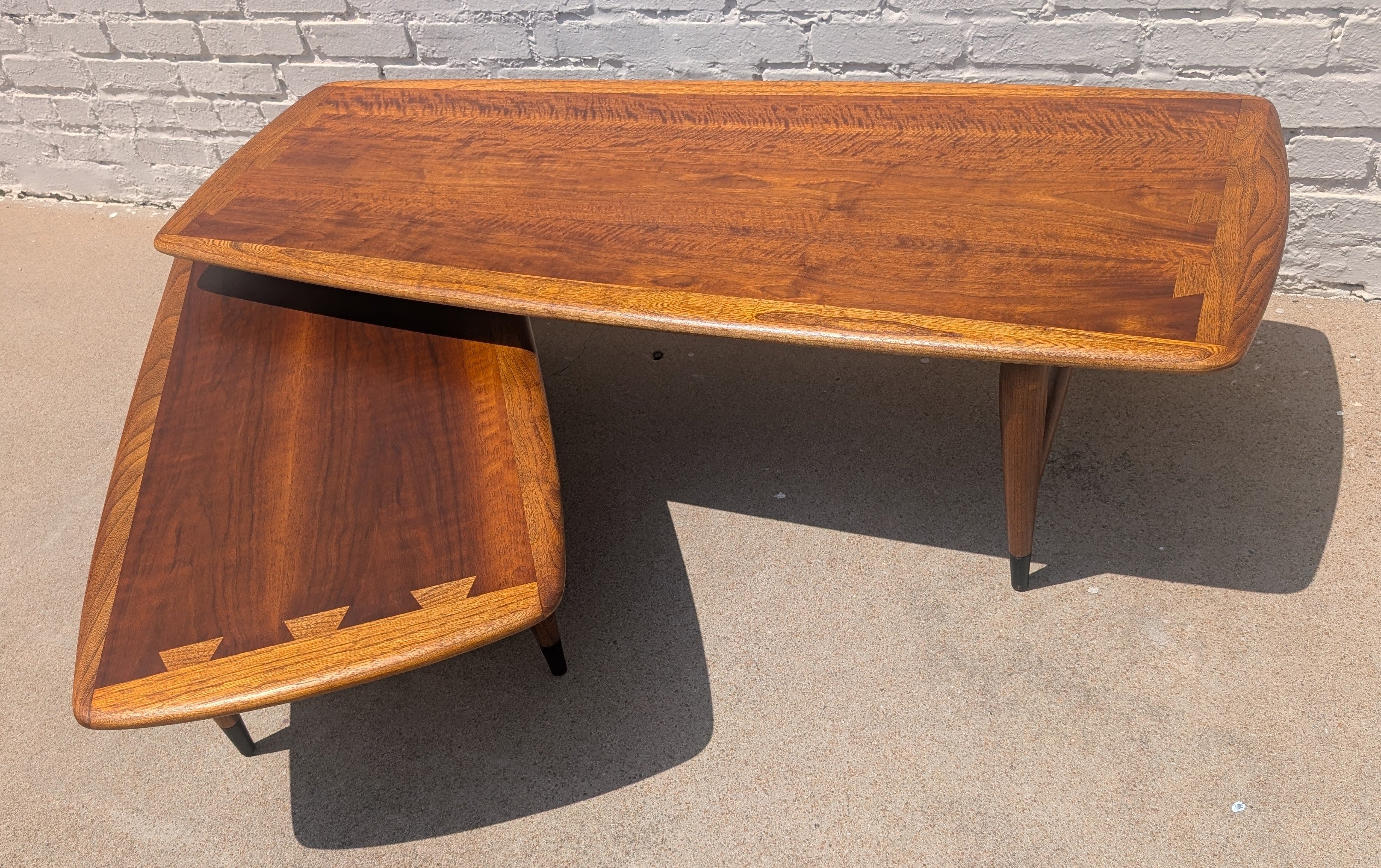 Wooden table with a matching smaller table on a concrete surface with a brick wall background