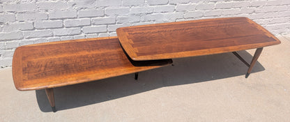 Wooden coffee table with a reflective surface on a concrete floor against a white brick wall.