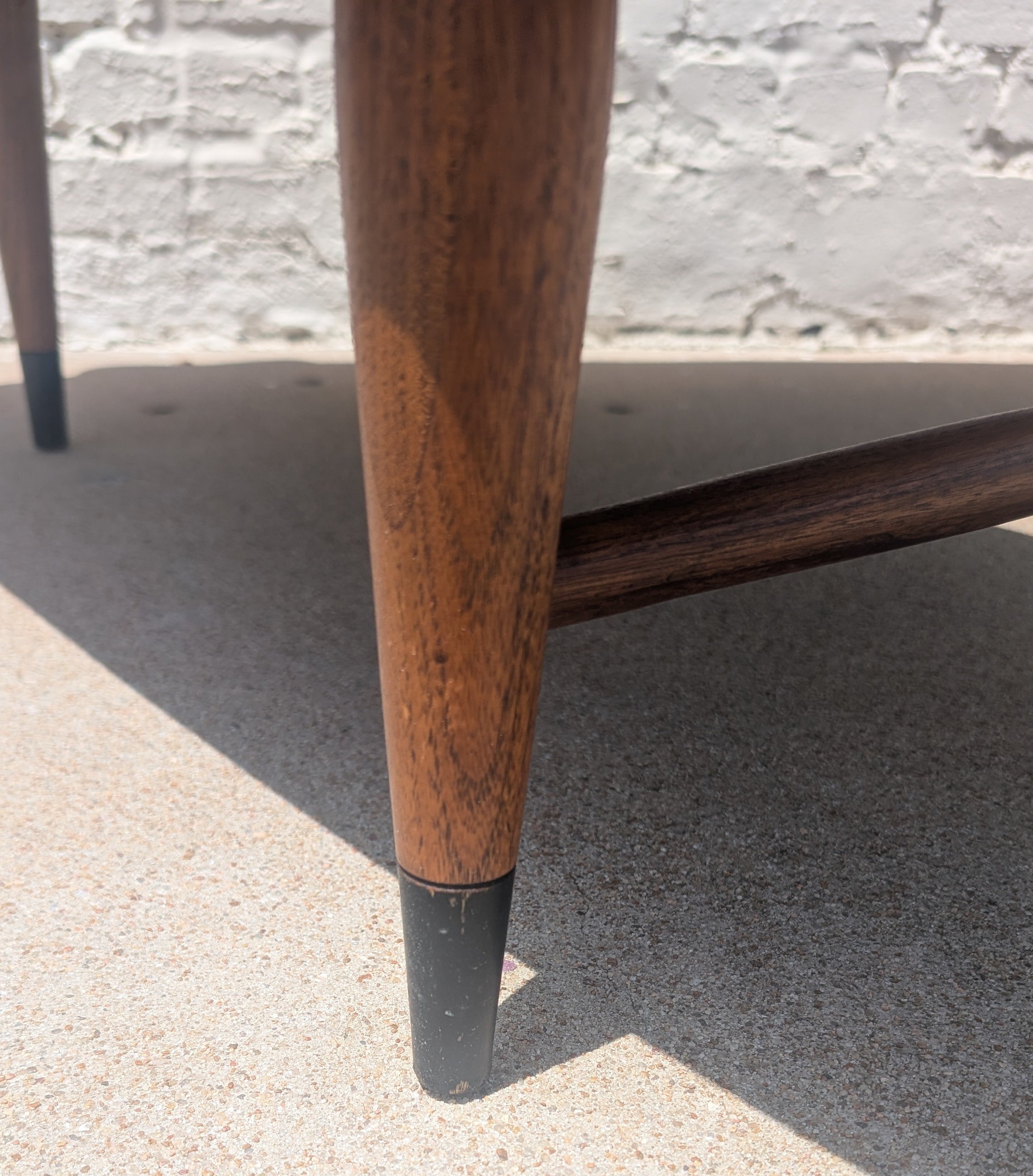 Close-up of a wooden leg with black base on a concrete surface.